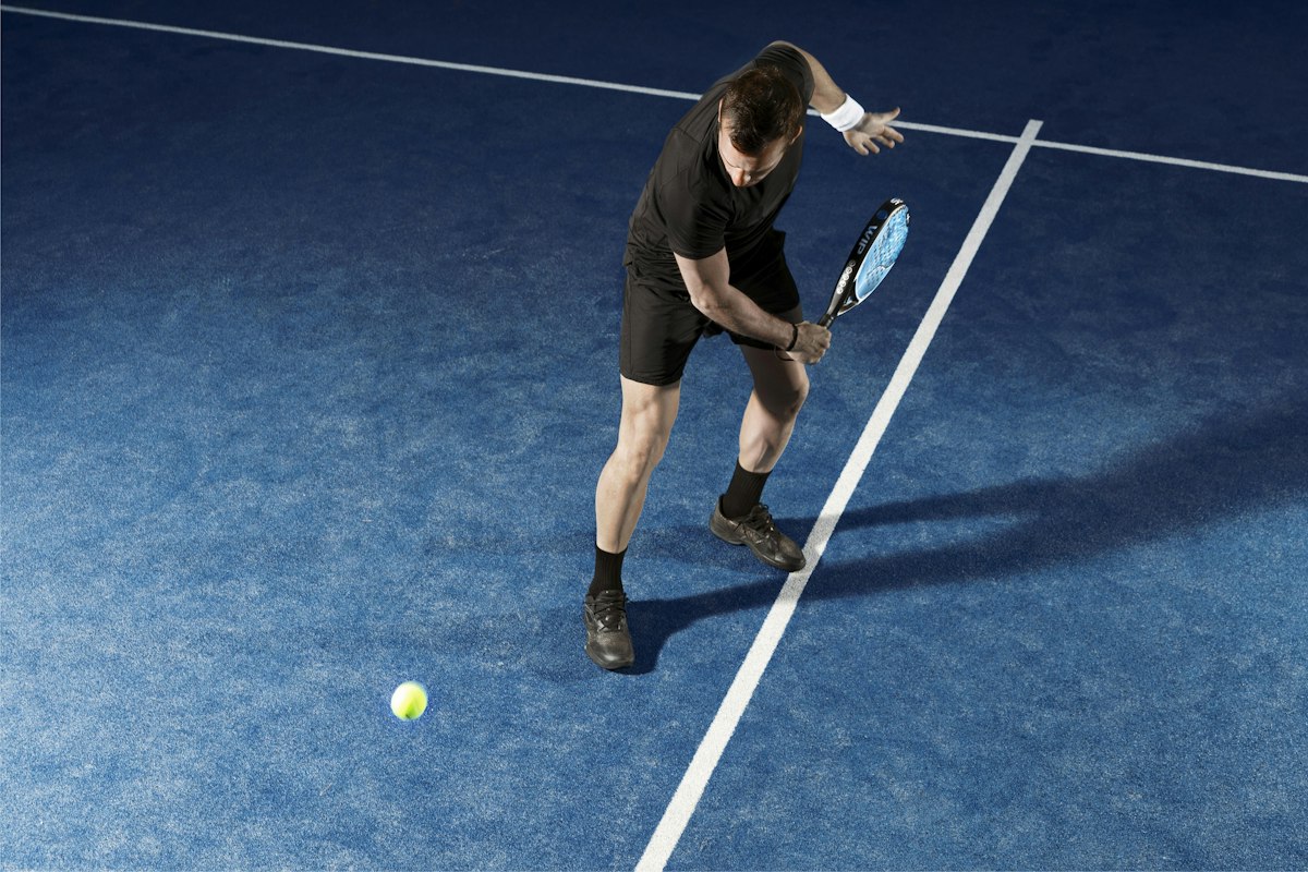 Jugador de pádel entrenando en cancha azul